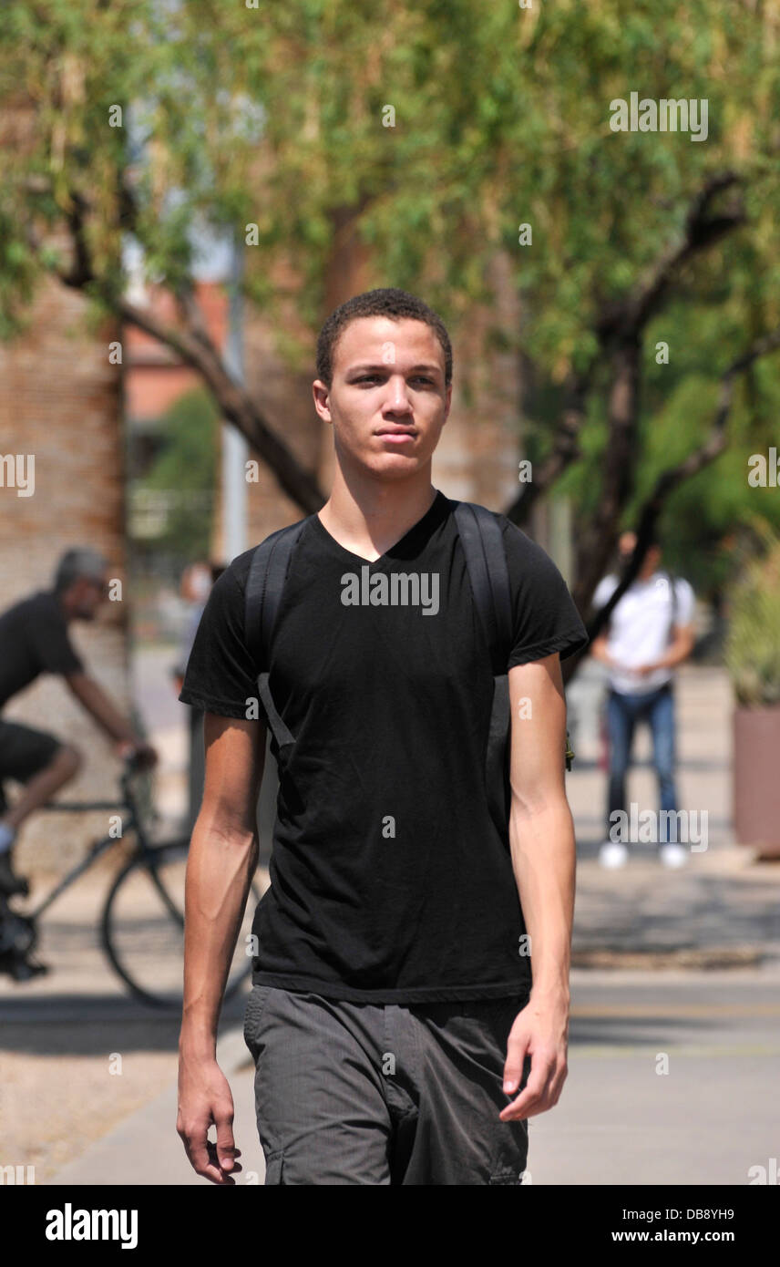 Un giovane uomo cammina su un campus universitario. Foto Stock