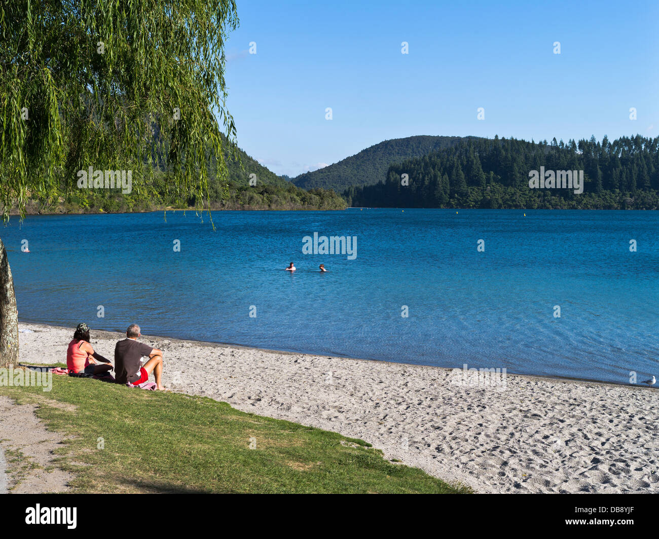 dh Lake Tikitapu Blue Lake ROTORUA NUOVA ZELANDA coppia seduta relax a riva nuotatori vacanze laghi laguna Foto Stock