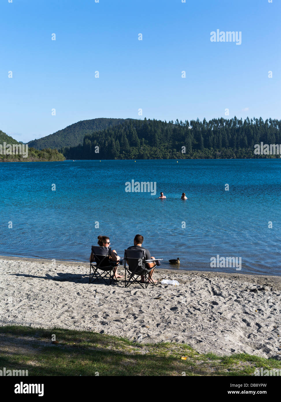 Dh Lago Blu Tikitapu Lago Rotorua Nuova Zelanda giovane sedie relax sulle rive nuotatori laguna di vacanza Foto Stock