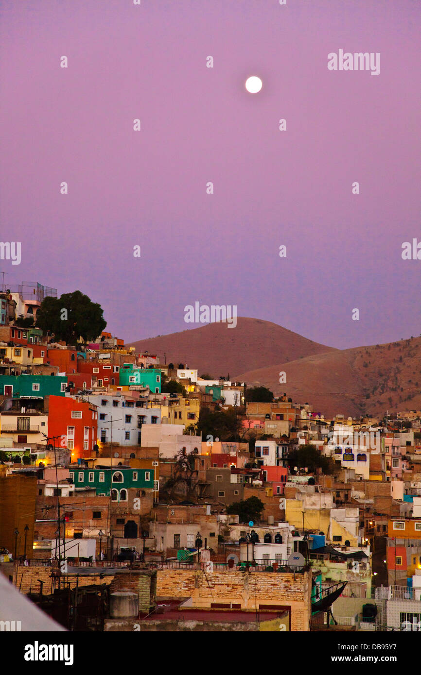 La luna piena sorge sopra le case colorate sul pendio della città culturale di Guanajuato in Messico centrale Foto Stock
