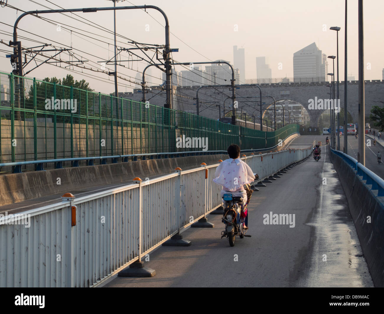 Donna su scooter corse in Nanjing città attraverso Changganmen, un cancello restaurato da Ming parete della città Foto Stock