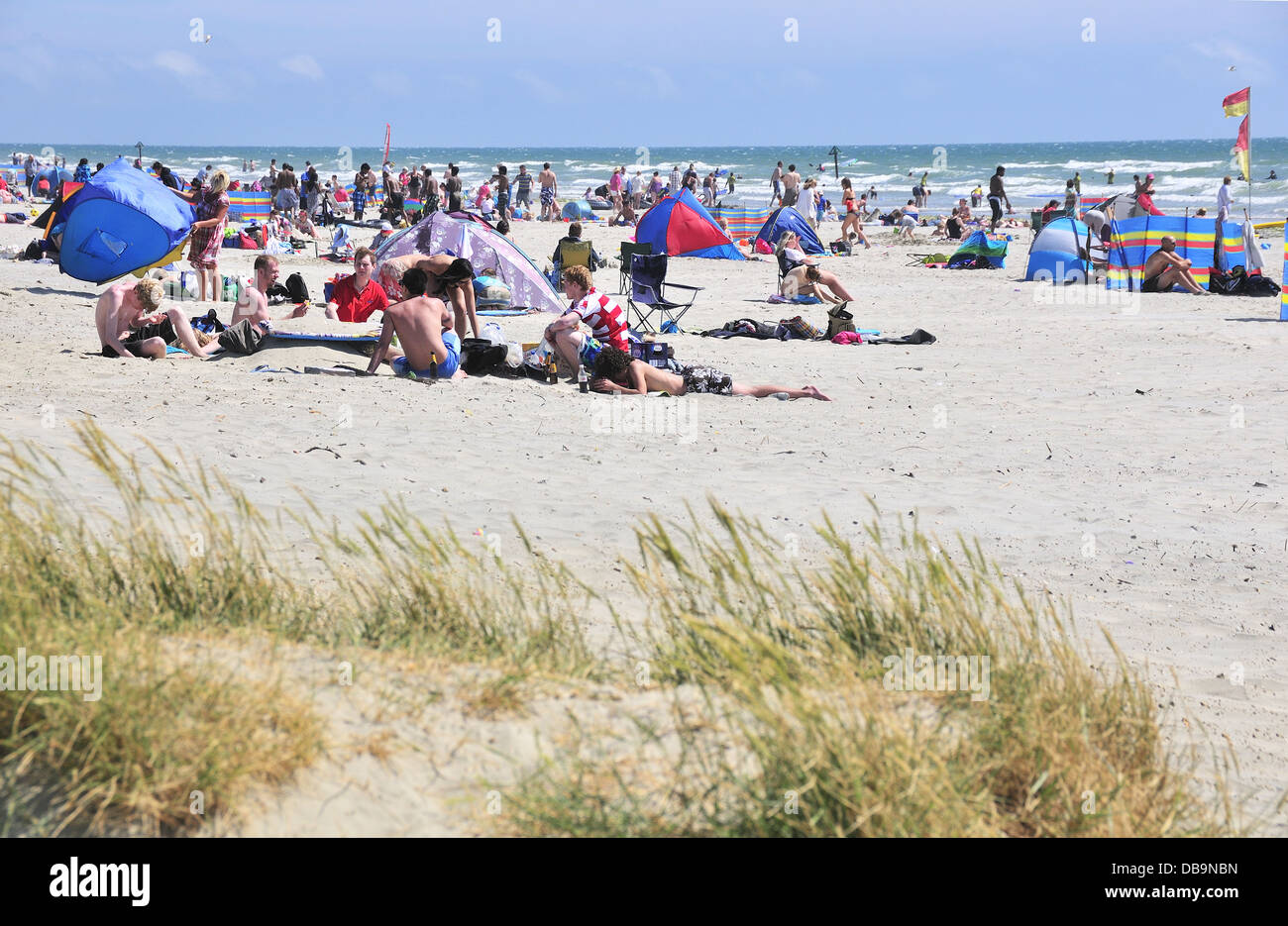 I villeggianti godendo di una calda giornata sulla bandiera blu spiaggia sabbiosa a West Wittering, vicino a Chichester, West Sussex, Regno Unito Foto Stock
