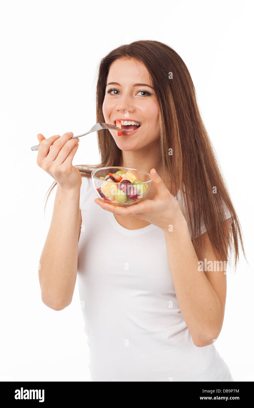 Bella donna mangiare frutta con una forchetta, isolato su bianco Foto Stock