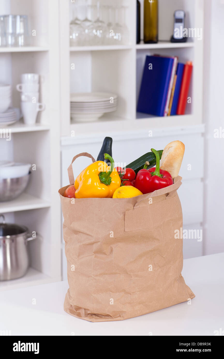 Carta shopping bag pieno di cibo su un banco di cucina Foto Stock