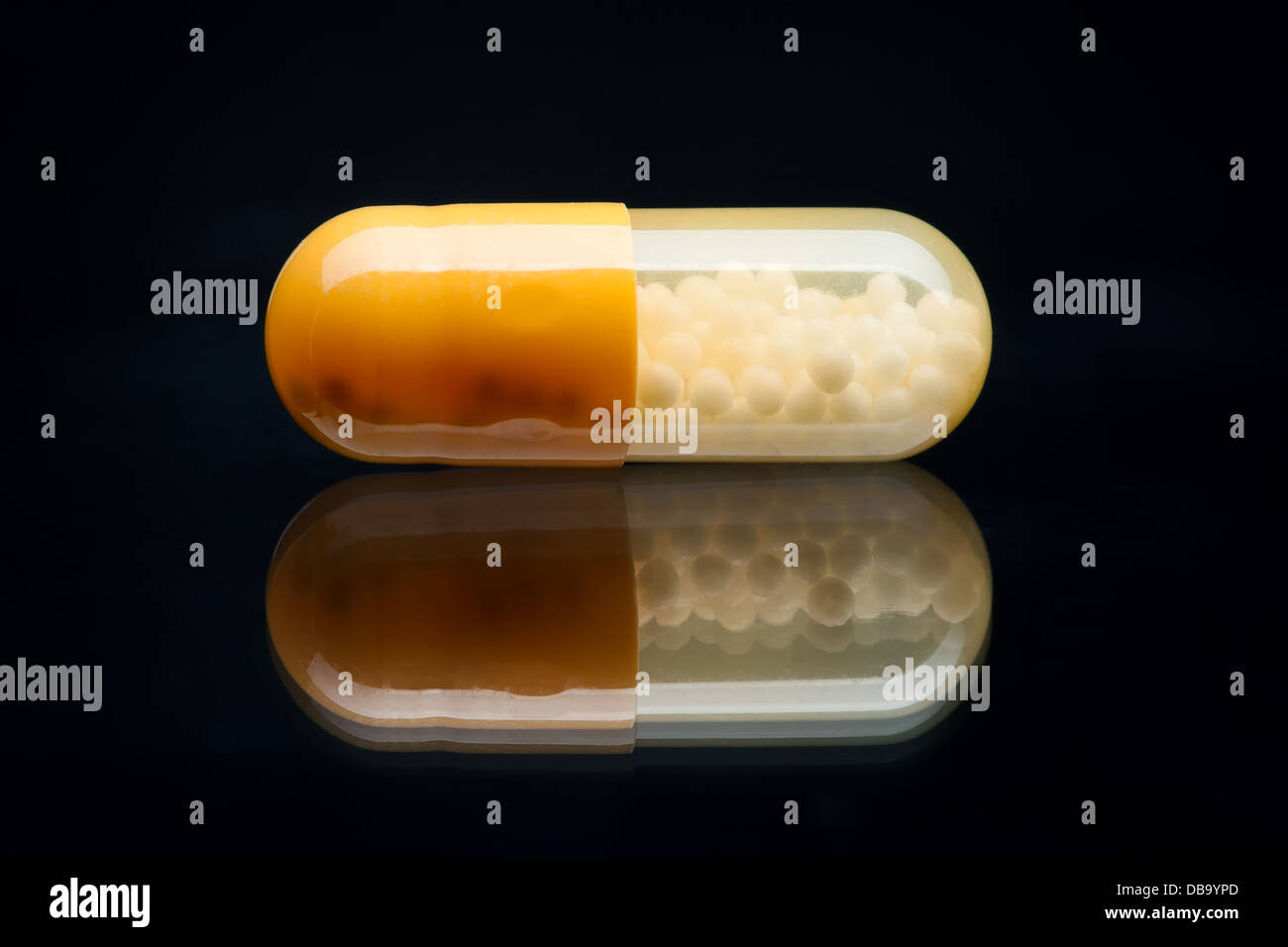 Giallo e Bianco pillola (capsula) macro shot con una riflessione, isolato su nero Foto Stock