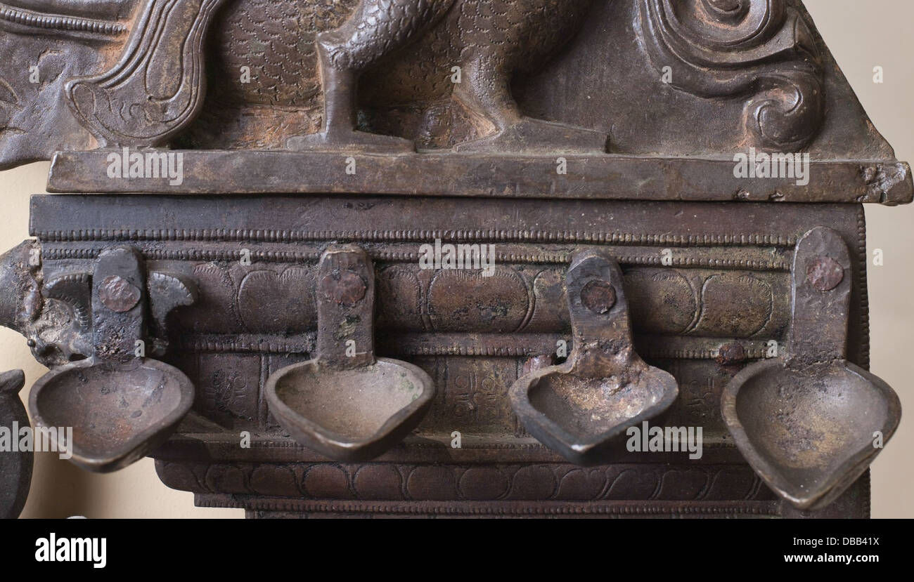 Questa arcata del tempio presenta figure intricate intagliate di animali di buon auspicio e fiancheggiano lampade a olio. La struttura riflette il simbolismo religioso e culturale, offrendo una visione delle antiche pratiche architettoniche e rituali. Foto Stock