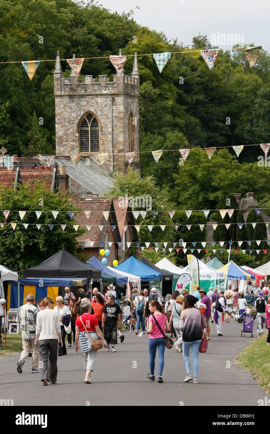 Milton Abbas, Dorset, Regno Unito. Il 27 luglio 2013. Milton Abbas è stata chiusa al traffico in quanto gli abitanti del villaggio e i visitatori intensificato indietro nel tempo per godere del xviii secolo Street Fair dove gli abitanti di un villaggio e i titolari di stallo in costumi tradizionali. La città originale (chiamato Middleton) fu demolita e spostata nella valle successiva perché Giuseppe Damer (poi Signore Milton 1° Conte di Dorchester) non mi piaceva la sua vicinanza con la sua grande casa. La fiera che si tiene ogni anno, è stato rilanciato quando presente giorno residenti ha voluto celebrare la fondazione del nuovo villaggio di Milton Abbas. Credito: Tom Corban/Alamy Live Foto Stock