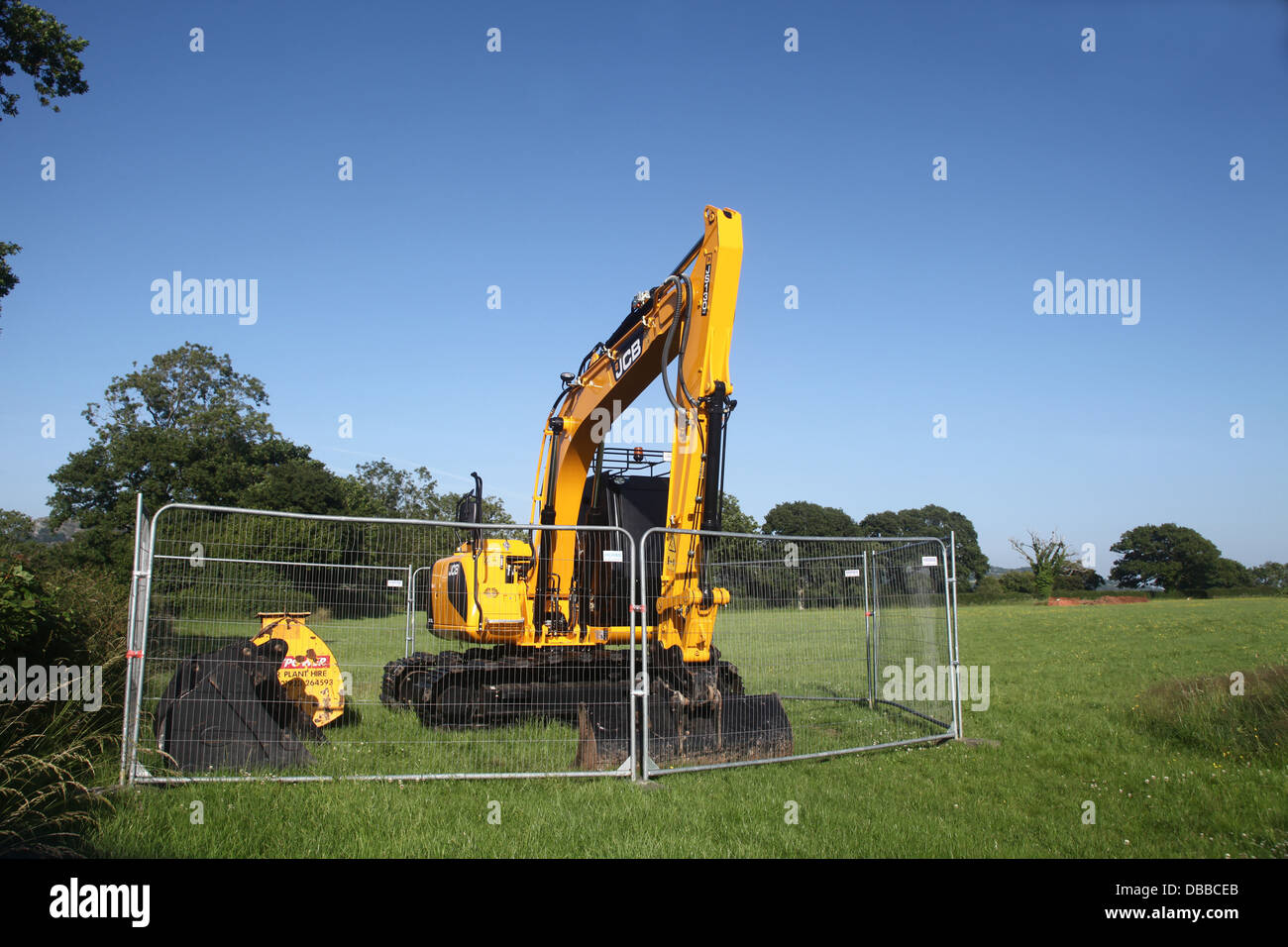 Grande escavatore giallo parcheggiato in un campo sotto un cielo blu chiaro, Luglio 2013 Foto Stock