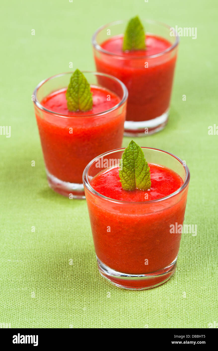 Tre piccoli bicchieri di frullato fragole su uno sfondo verde Foto Stock