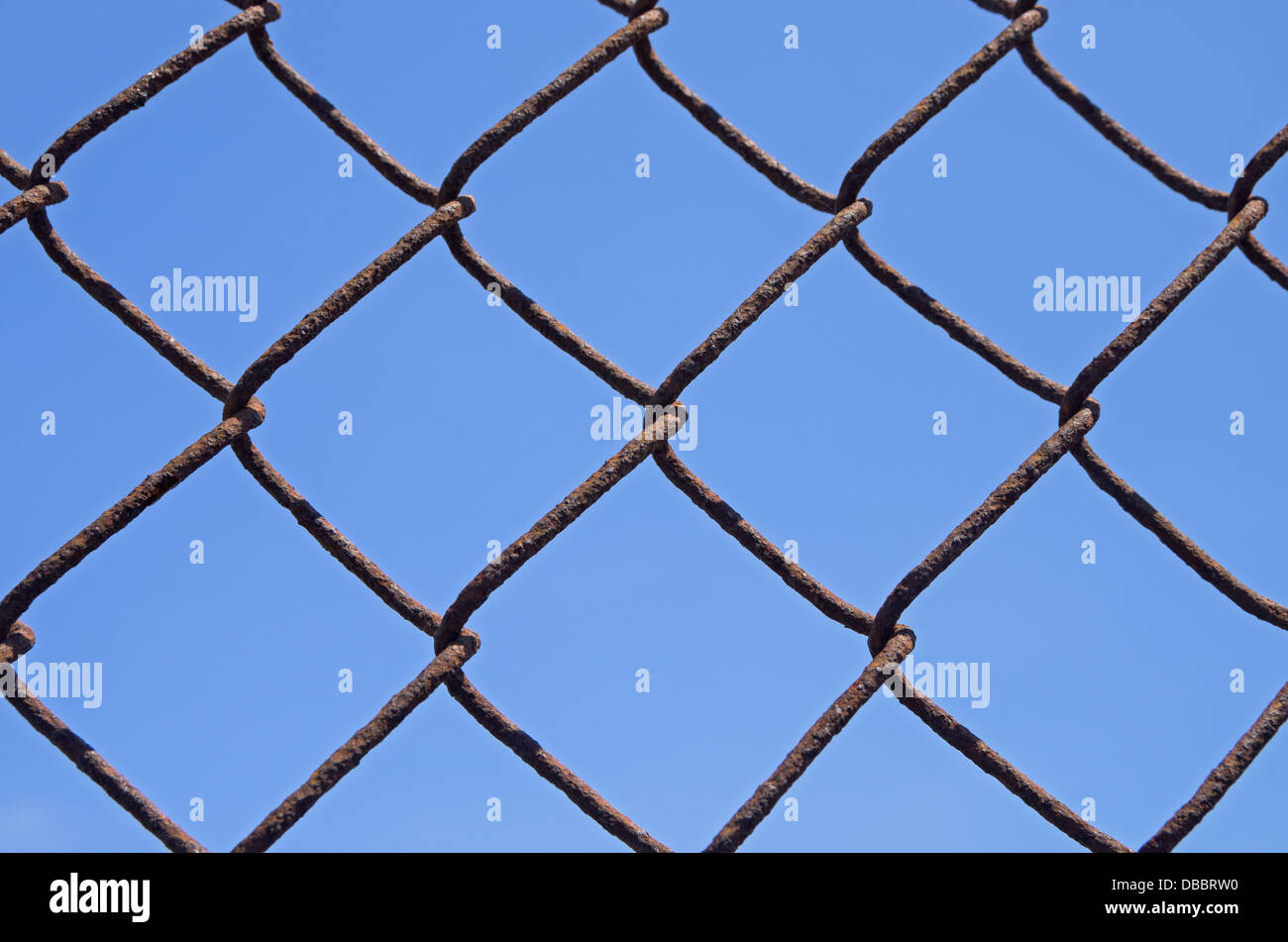 Dettaglio di un arrugginito catena collegamento recinto con cielo blu sullo sfondo Foto Stock