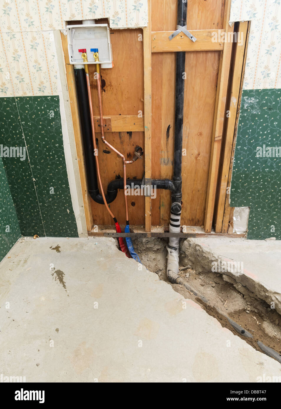 La rondella collegamento di installazione in una casa rimodellare con soletta di calcestruzzo trincea e nuova acqua e tubi di scarico installato Foto Stock