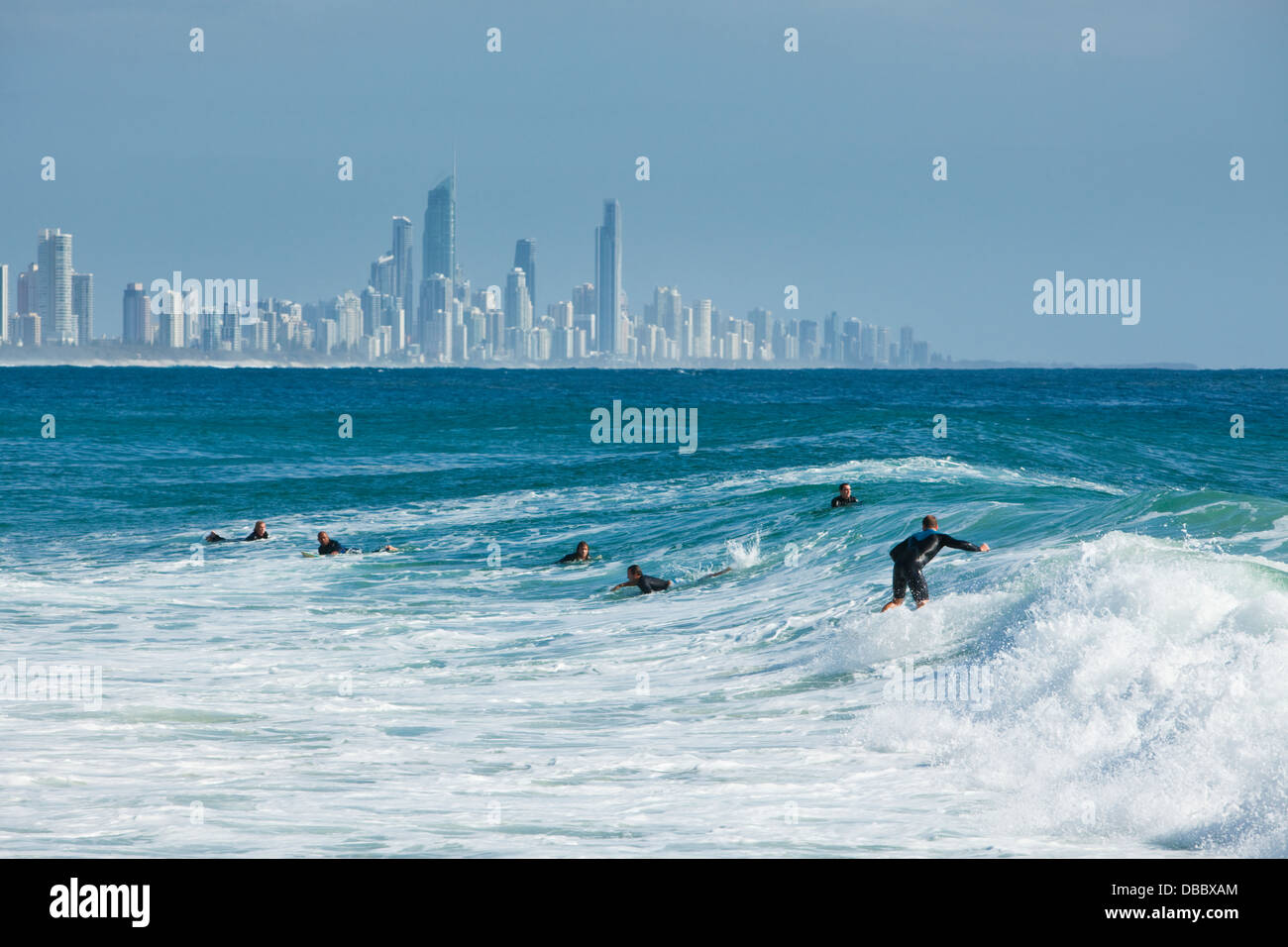 Surfer a cavallo di un onda con Surfers Paradise skyline in background. Burleigh capi, Gold Coast, Queensland, Australia Foto Stock