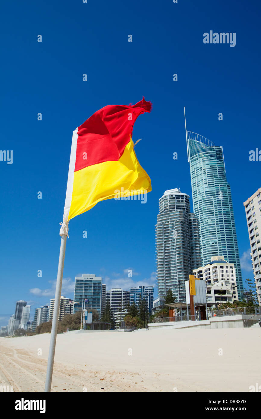 Surf lifesaving bandiera con lo skyline della città in background. Surfers Paradise, Gold Coast, Queensland, Australia Foto Stock