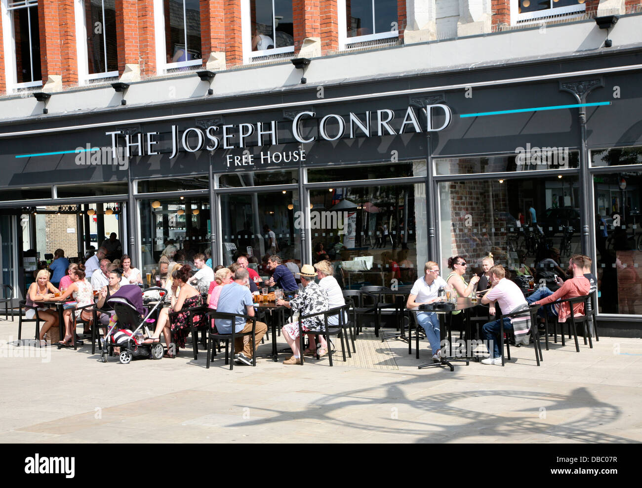 La gente seduta al di fuori del Joseph Conrad pub Wetherspoons Lowestoft Suffolk Inghilterra convertito da ex-shop Foto Stock