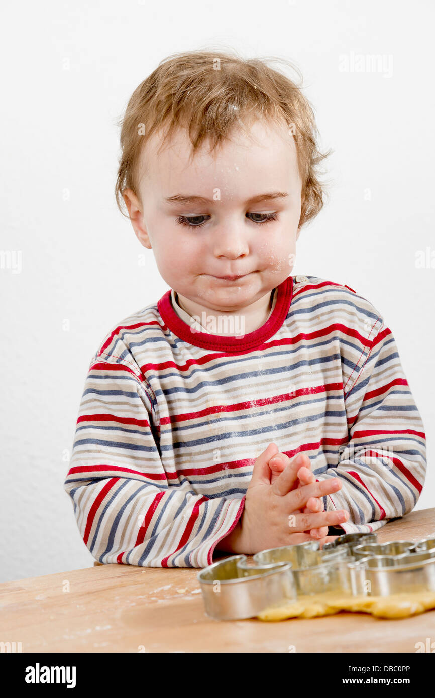 Un giovane bambino nell'immagine verticale guardando gli strumenti di cottura e di pasta Foto Stock