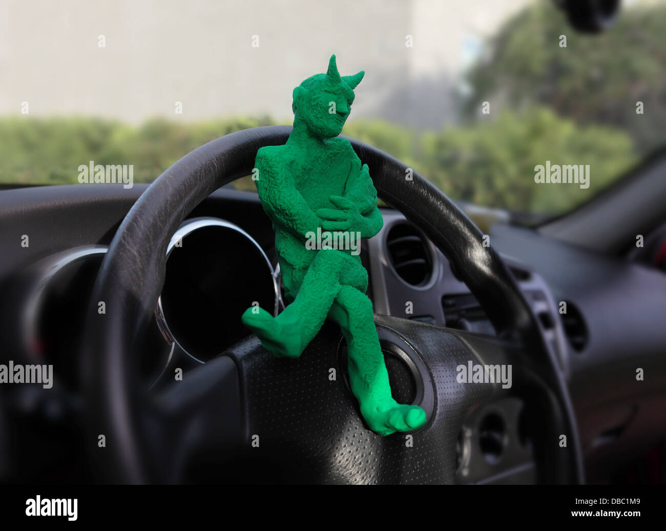 Un po' di verde devil fatti di argilla, si siede al volante di una vettura...egli è in attesa di qualcuno che afferra il volante. Foto Stock