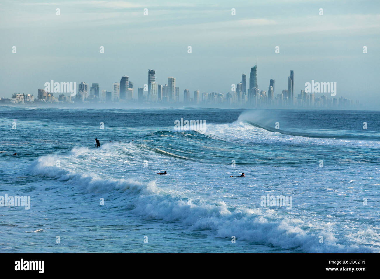 Surfisti in mattinata si gonfiano con Surfers Paradise skyline in background. Burleigh capi, Gold Coast, Queensland, Australia Foto Stock