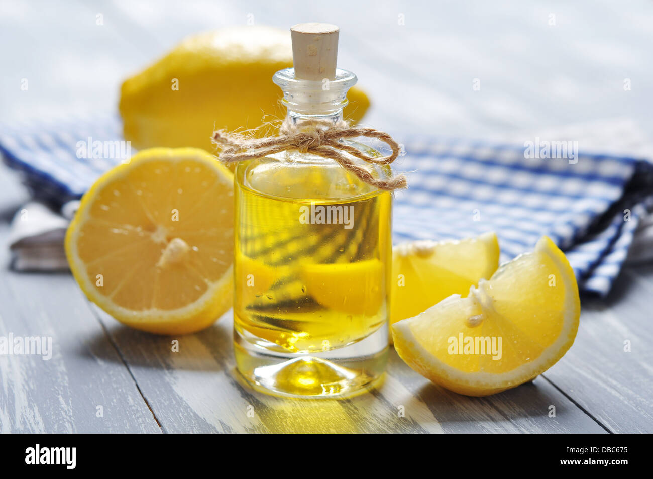 Olio di limone in una bottiglia di vetro con fresco лемон он sfondo di legno Foto Stock
