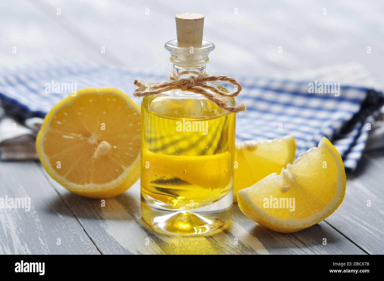 Olio di limone in una bottiglia di vetro con fresco лемон он sfondo di legno Foto Stock