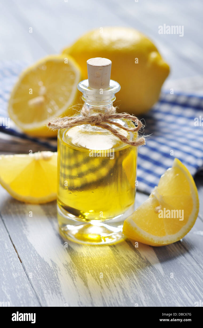 Olio di limone in una bottiglia di vetro con fresco лемон он sfondo di legno Foto Stock