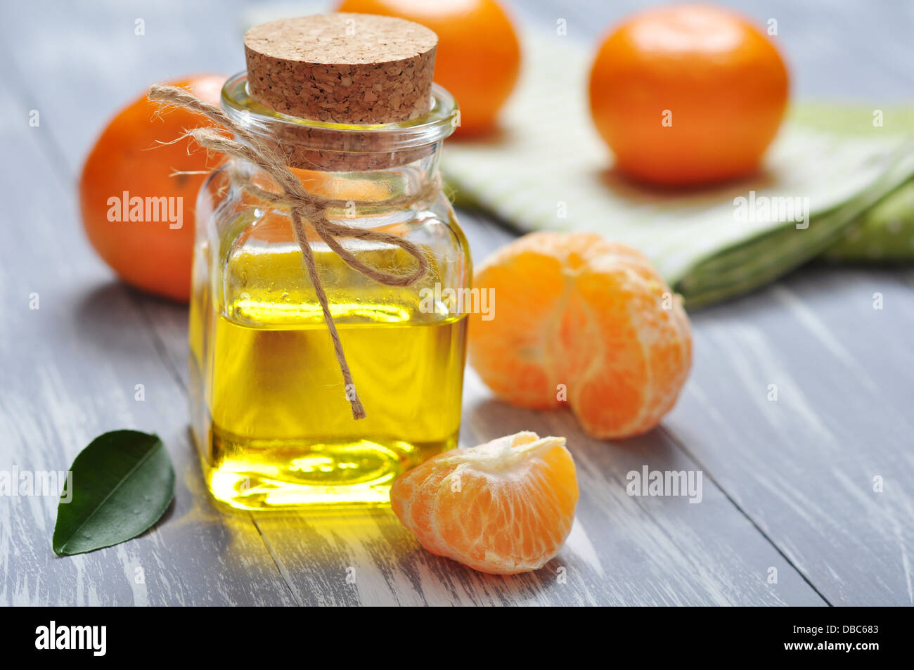Tangerine olio in una bottiglia di vetro con fresco mandarino он sfondo di legno Foto Stock