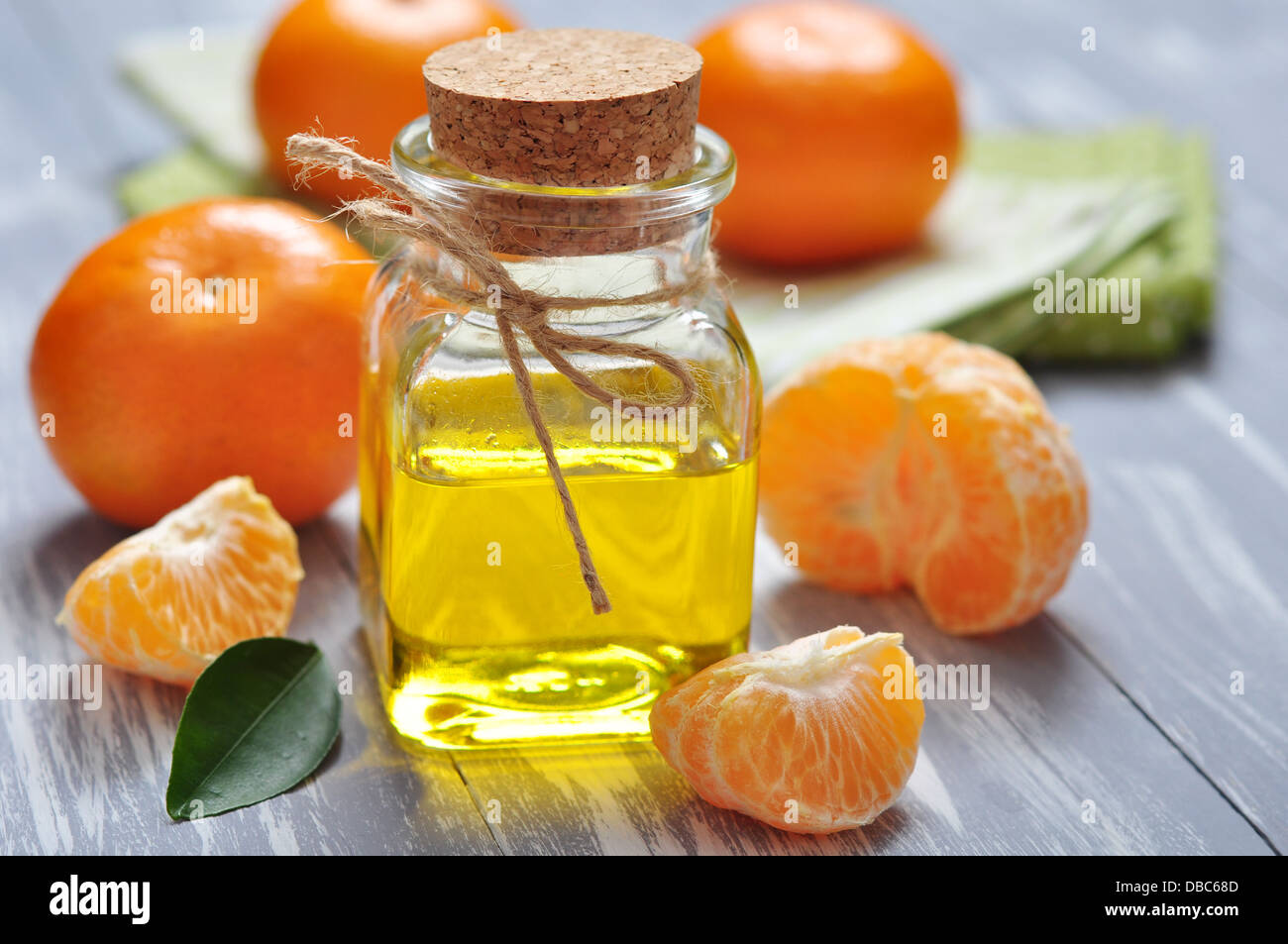Tangerine olio in una bottiglia di vetro con fresco mandarino он sfondo di legno Foto Stock