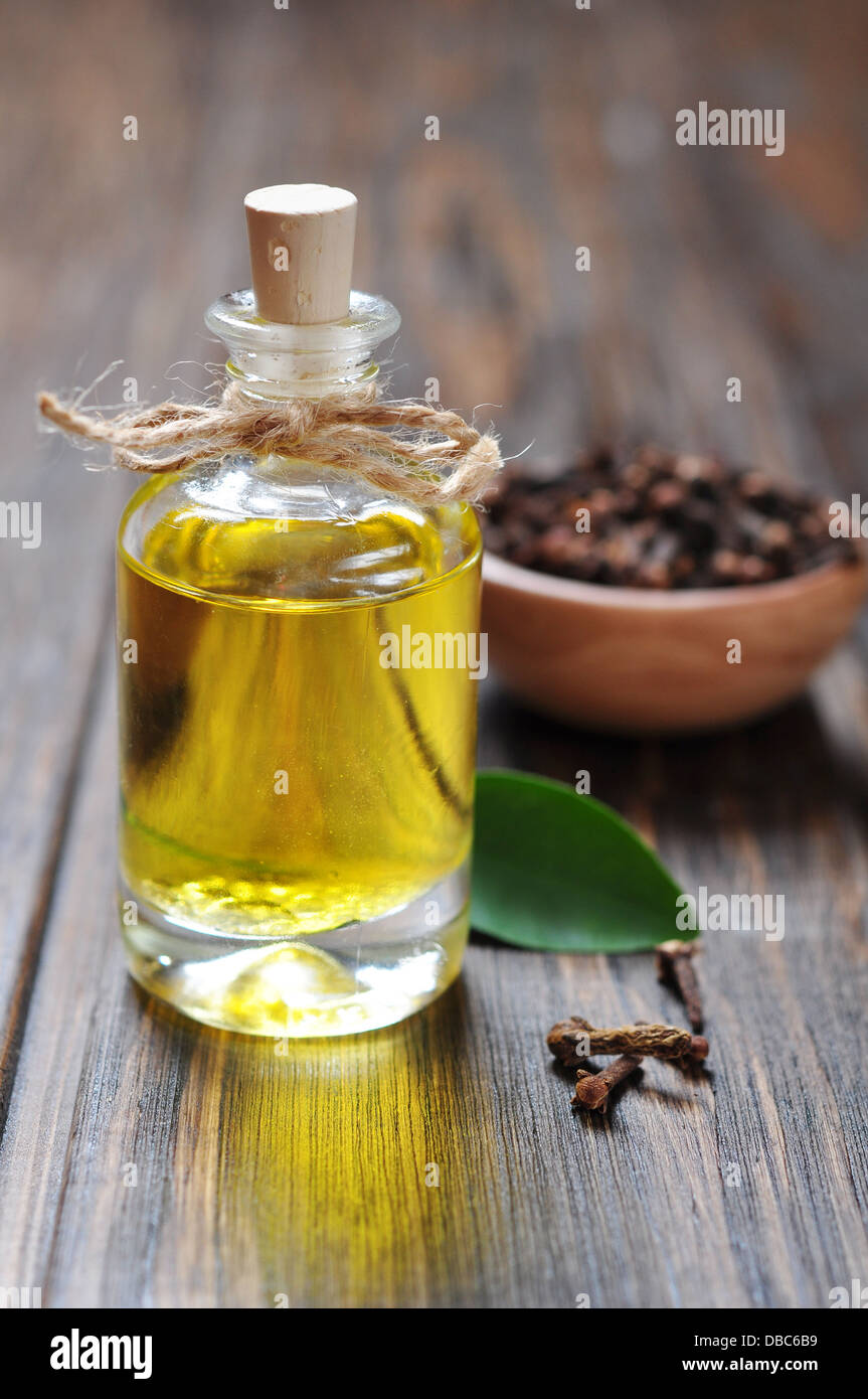 Olio di chiodi di garofano in una bottiglia di vetro sopra lo sfondo di legno Foto Stock