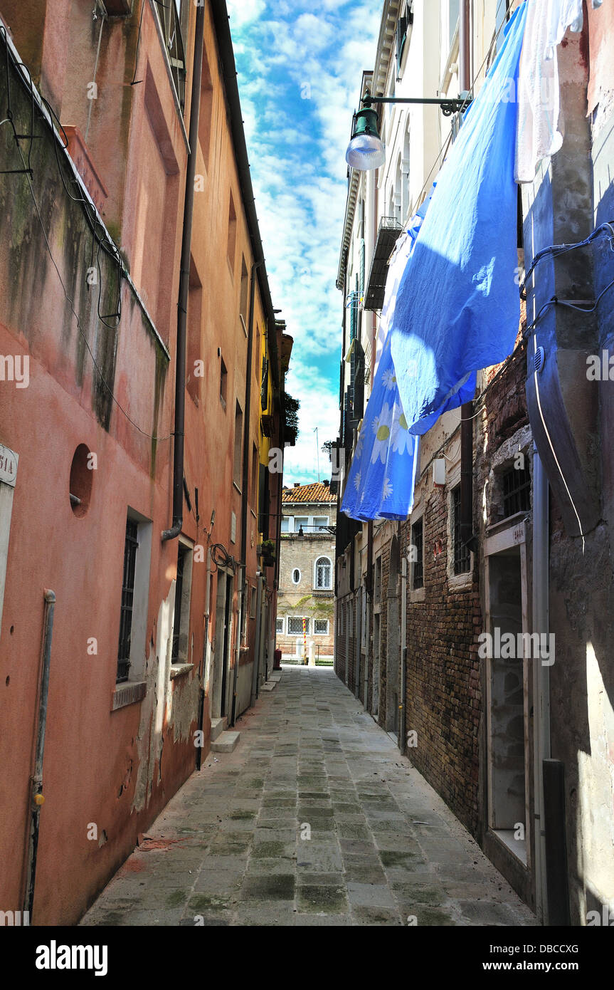 Piccola strada con lenzuola blu appese ad asciugare il giorno di sole fuori case a Venezia, Venezia, Veneto, Italia, Europa Foto Stock