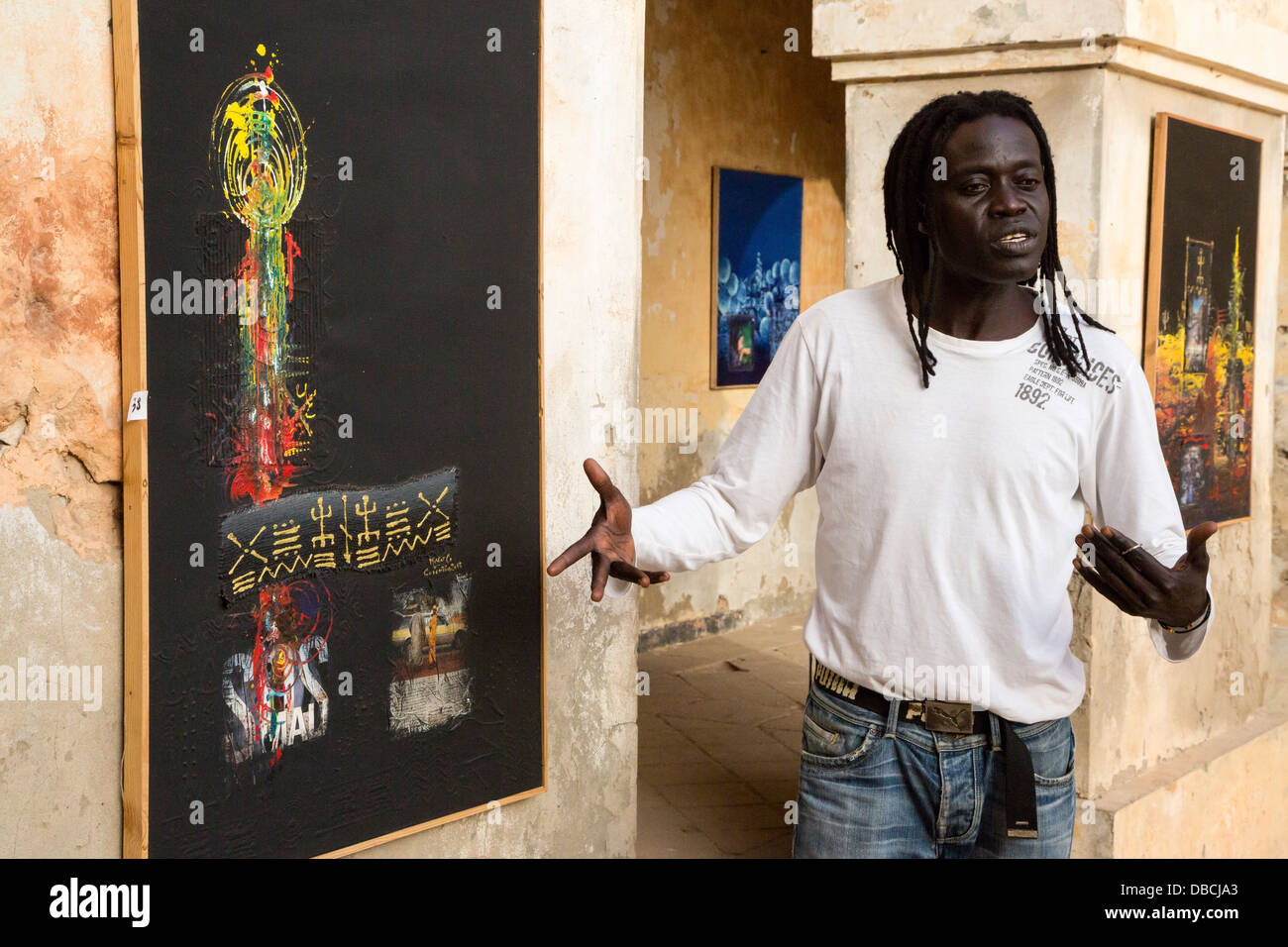 Artista 'Mr. Co' (Corentin Faye) spiega la sua pittura, semestrale Arts Festival, isola di Goree, Senegal. Foto Stock