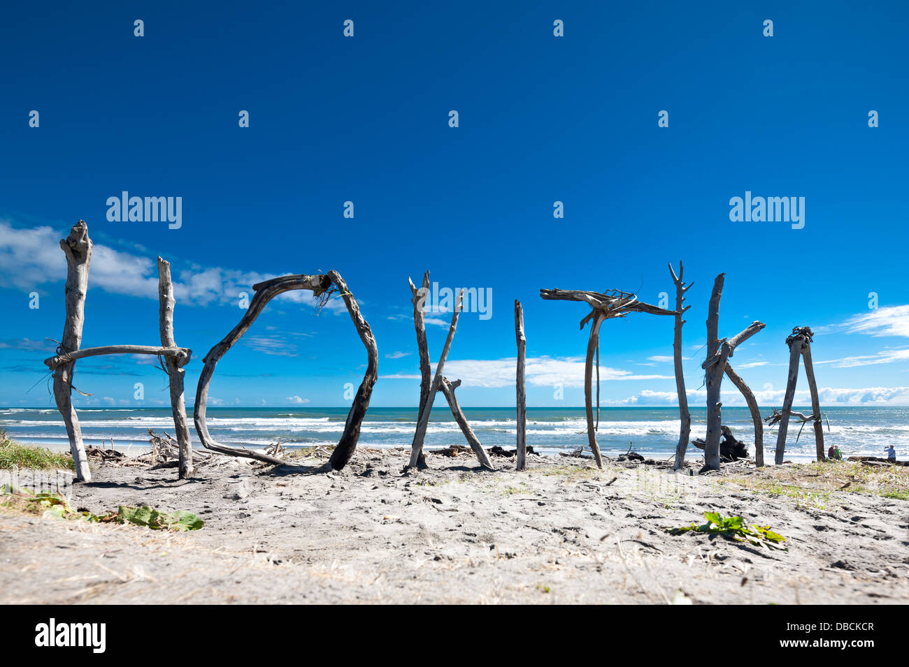 Hokitika. Driftwood scultura; nome della città segno scolpito dal trovato deriva su legno Hokitika Beach, Isola del Sud, Nuova Zelanda Foto Stock