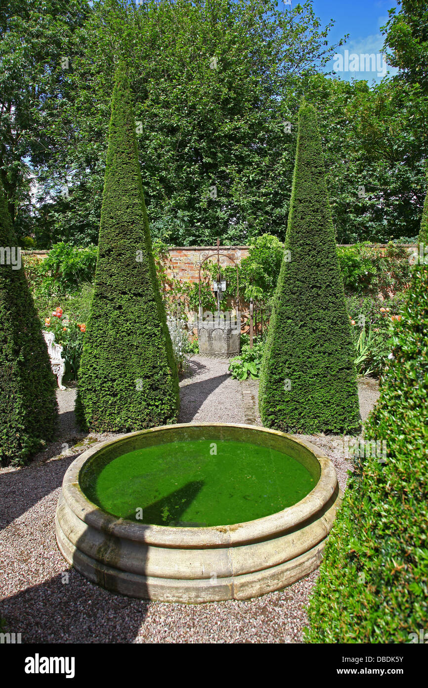Ritagliato yew guglie e bene a Wollerton Old Hall Giardini Giardino Wollerton Market Drayton Shropshire England Regno Unito Foto Stock