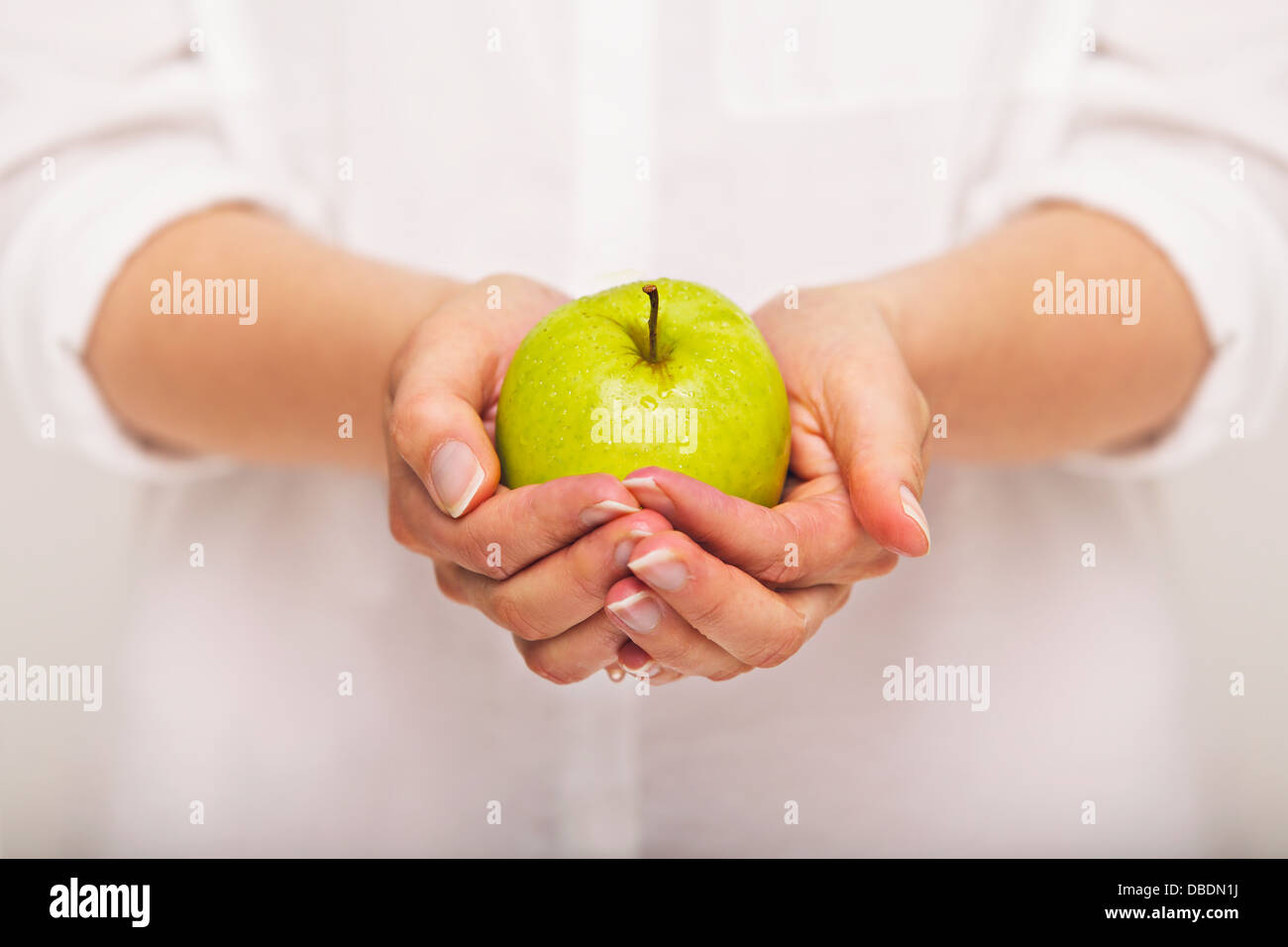 Donna con una mela verde in mani Foto Stock