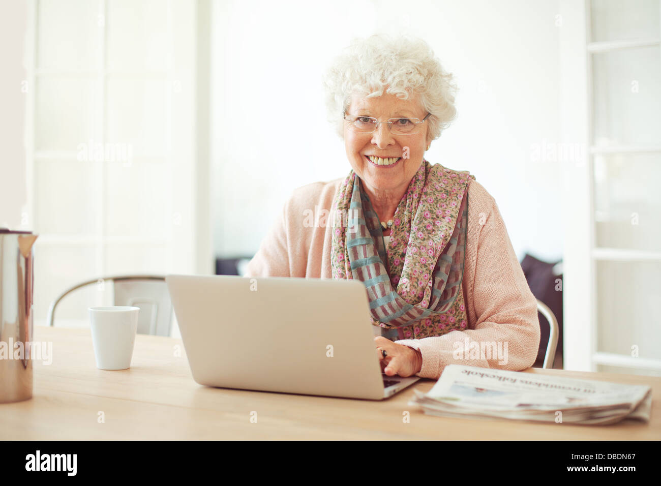 Allegra donna senior utilizzando laptop come ricreazione a casa Foto Stock