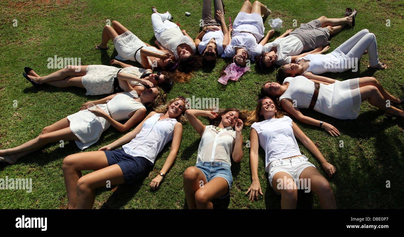 12 giovani donne in bianco formando un cerchio Foto Stock