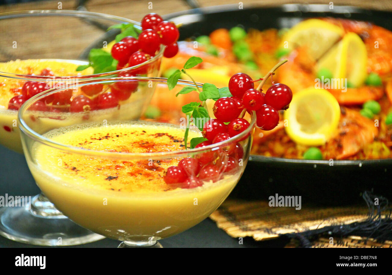 Crema catalana con frutti rossi e cucina di mare paella su un menu presentazione. Entrambi sono molto popolari piatti in Spagna Foto Stock