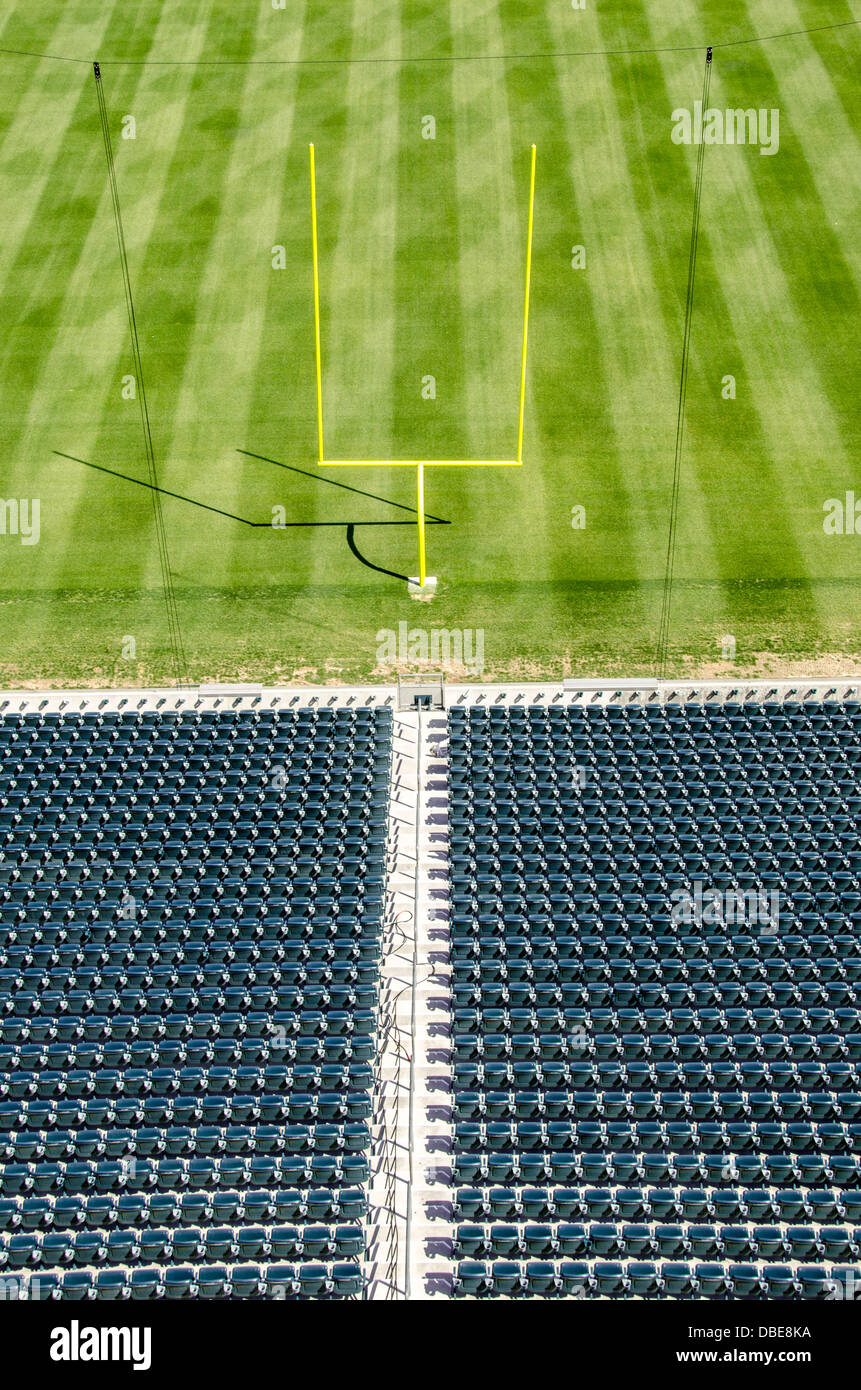 Stadio di football con posti a sedere vuoti Goal Posts United States // UNITED STATES - uno stadio di calcio professionistico vuoto presenta il suo campo da gioco incontaminato, con erba meticolosamente curata e importanti pali di gol con le loro distintive traverse. I posti a sedere vuoti dello stadio si innalzano sullo sfondo, creando un'atmosfera di attesa per il ruggito della folla e l'eccitazione della giornata di gioco. Foto Stock