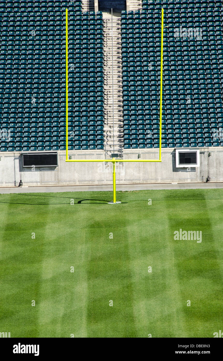 Stadio di football con posti a sedere vuoti Goal Posts United States // UNITED STATES - uno stadio di calcio professionistico vuoto presenta il suo campo da gioco incontaminato, con erba meticolosamente curata e importanti pali di gol con le loro distintive traverse. I posti a sedere vuoti dello stadio si innalzano sullo sfondo, creando un'atmosfera di attesa per il ruggito della folla e l'eccitazione della giornata di gioco. Foto Stock