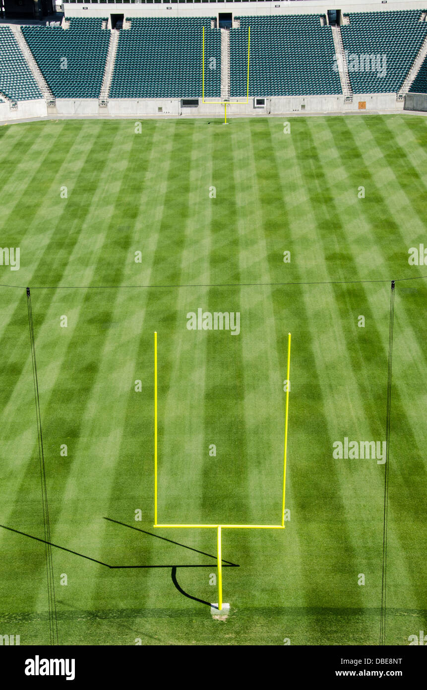 Football Stadium Empty Field Goal Posts United States // UNITED STATES - uno stadio di calcio professionistico vuoto presenta il suo campo da gioco incontaminato, con erba meticolosamente curata e importanti pali di gol con le loro distintive traverse. I posti a sedere vuoti dello stadio si innalzano sullo sfondo, creando un'atmosfera di attesa per il ruggito della folla e l'eccitazione della giornata di gioco. Foto Stock