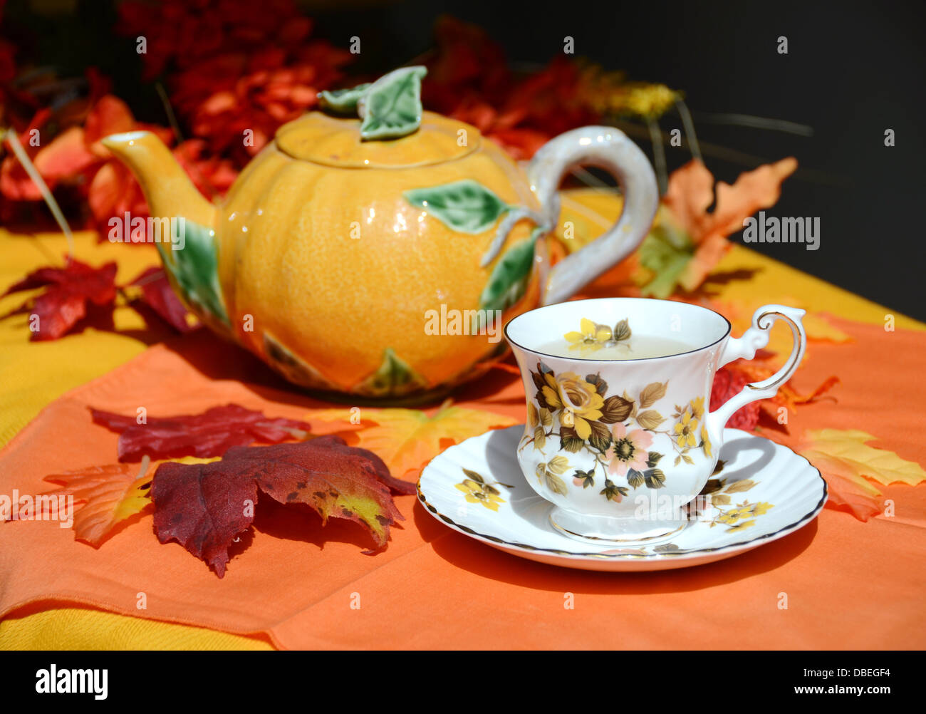 Una caduta a tema tazza di tè e una zucca tè pentola di sedersi su un autunno decorate Impostazione tabella Foto Stock
