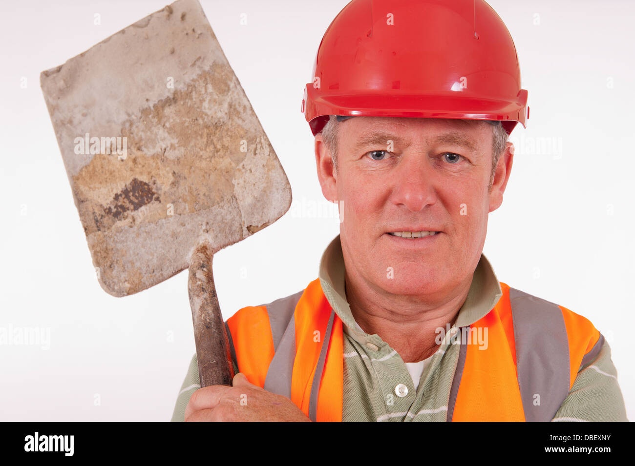 Sorridente builder indossando un disco Red Hat e portante una pala sulla sua spalla. Foto Stock