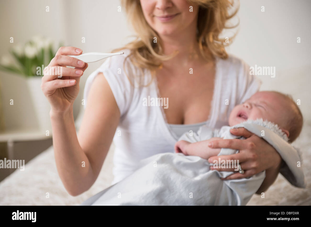 Madre caucasica tenendo il pianto temperatura del bambino Foto Stock