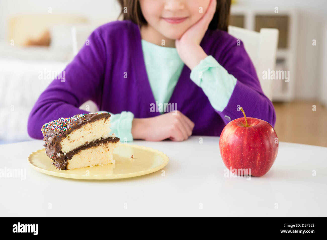 Razza mista ragazza scegliendo tra la torta e Apple Foto Stock