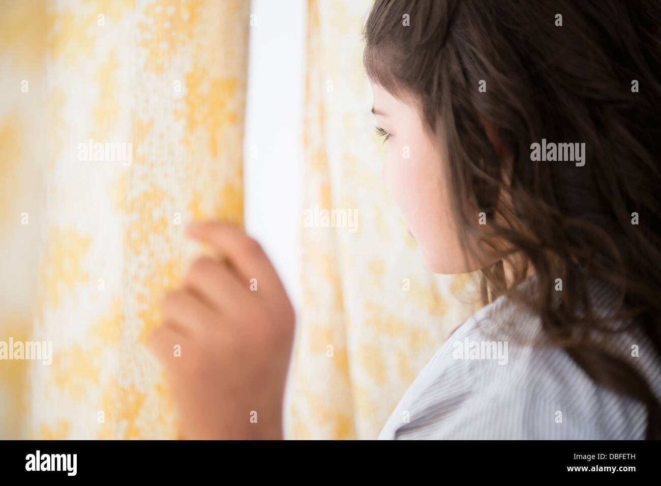 Ragazza ispanica a guardare fuori dalla finestra Foto Stock