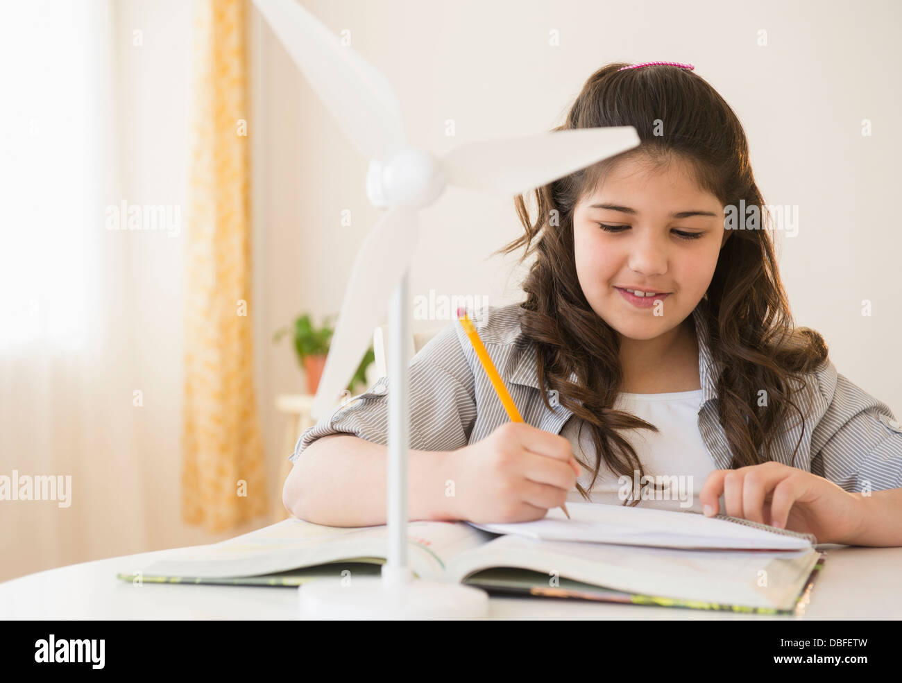 Ragazza ispanica con il modello di turbina eolica facendo i compiti di scuola Foto Stock