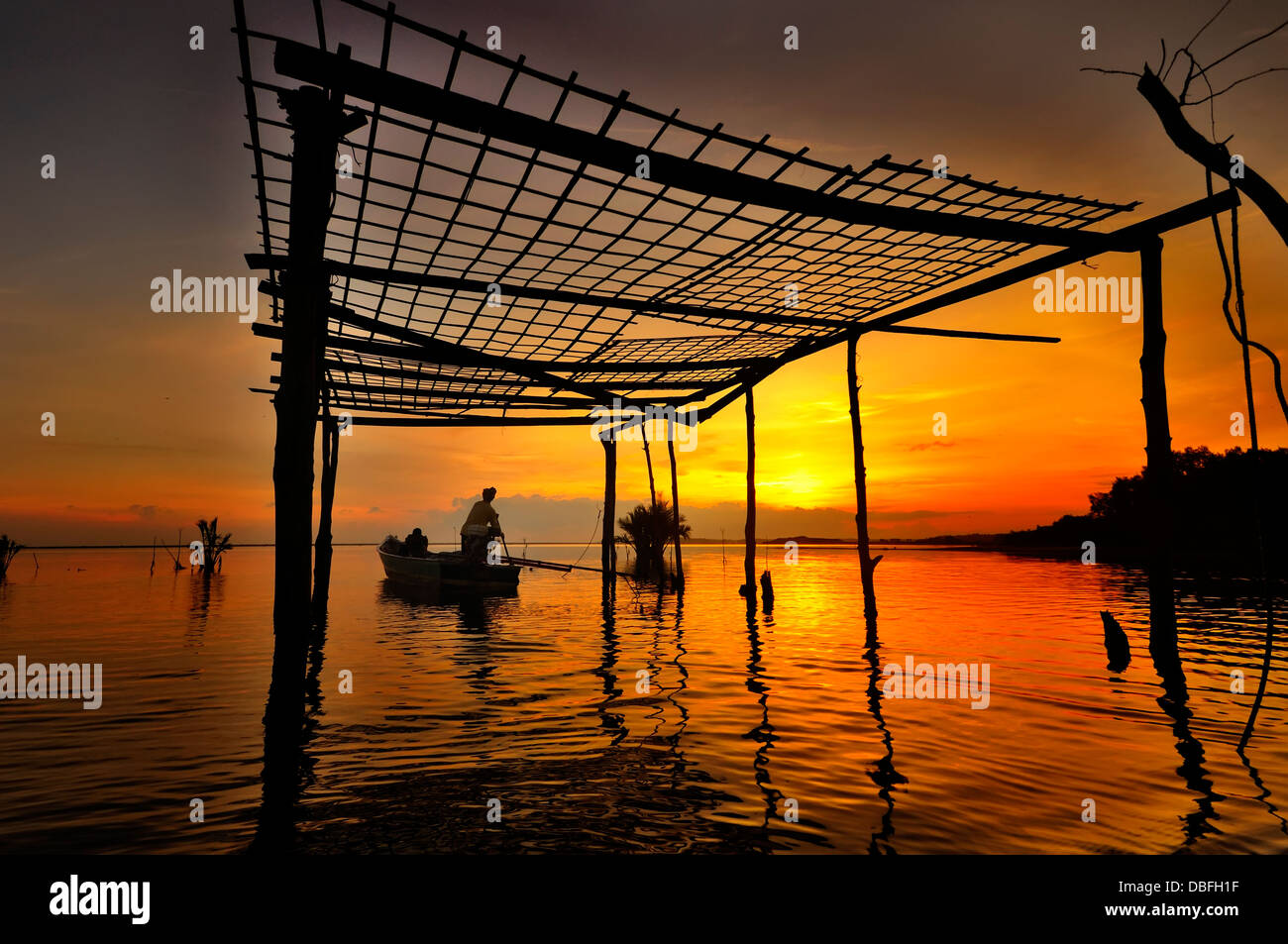 Silhouette pescatore sono barca a remi in barca da pesca di sunrise Foto Stock