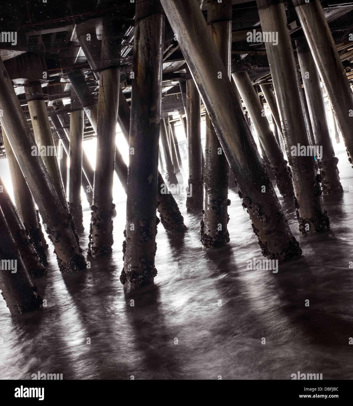 Colonne di legno di boardwalk in onde Foto Stock