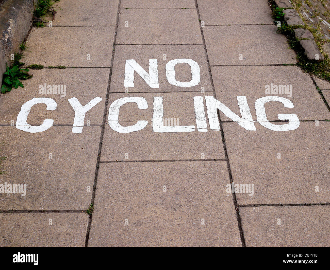 Un 'n' Ciclismo dipinte di avvertimento impresse stampata su un British marciapiede marciapiede. Nessuno. Foto Stock