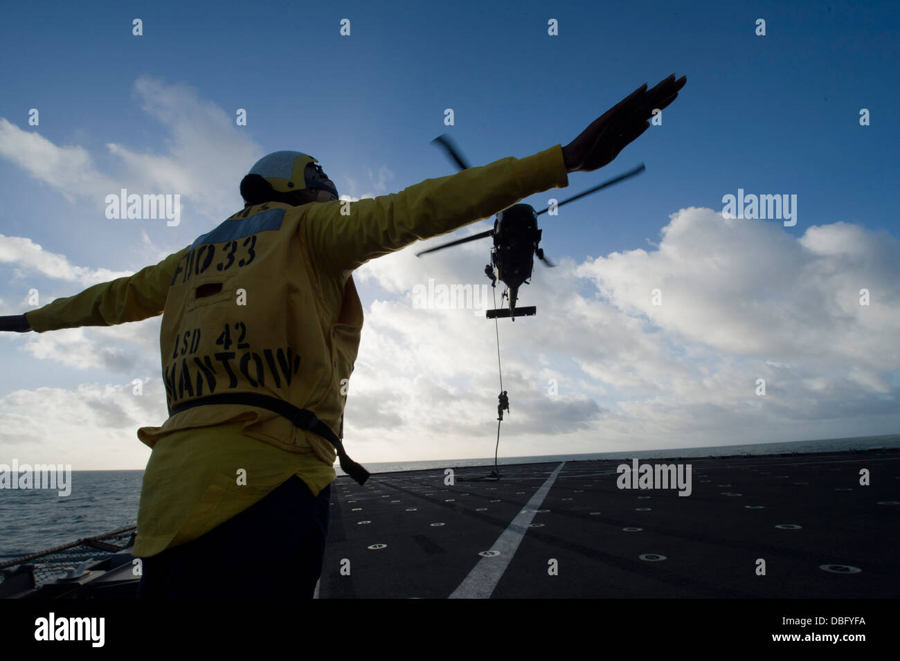 Di Boatswain Mate 2a classe Skiesha Chiesa segnali ad un esercito australiano S-70A-9 Falco nero come un esercito australiano soldato dal 2° reggimento di commando, domestici contro il terrorismo fast-rappels al dock landing ship USS Germantown (LSD 42). Germantown è su Foto Stock