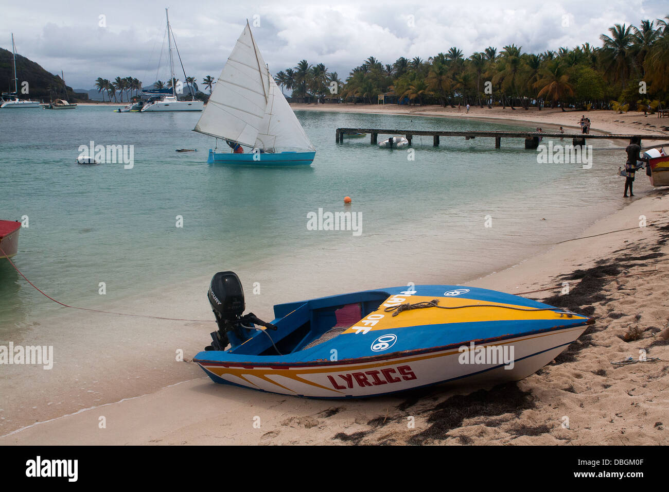 Vista di Salt Whistle Bay, la spiaggia e il molo con barche e palme, Mayreau, Caraibi Orientali. Foto Stock