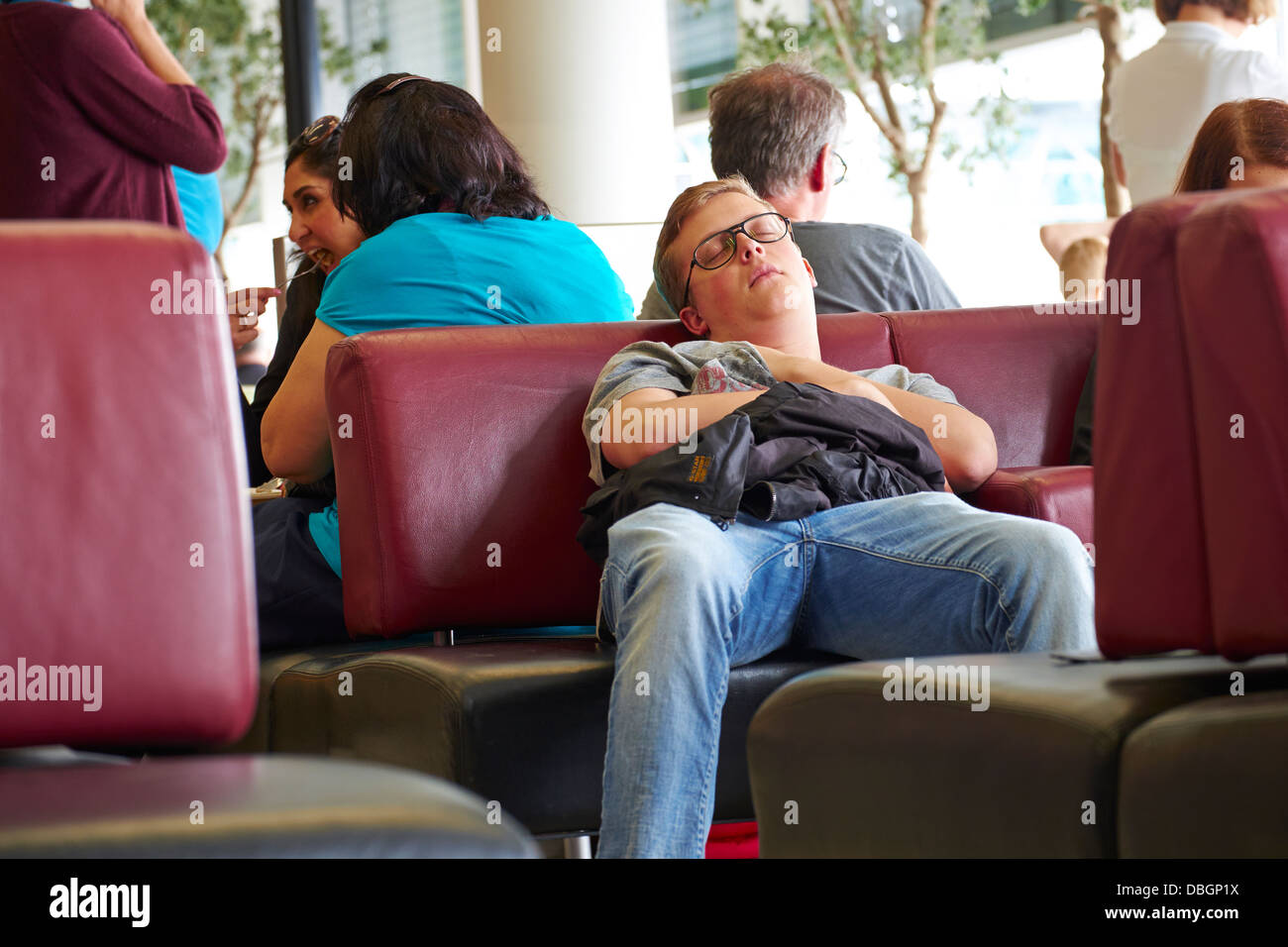 Un uomo dorme nella sala partenze dell'aeroporto. Foto Stock
